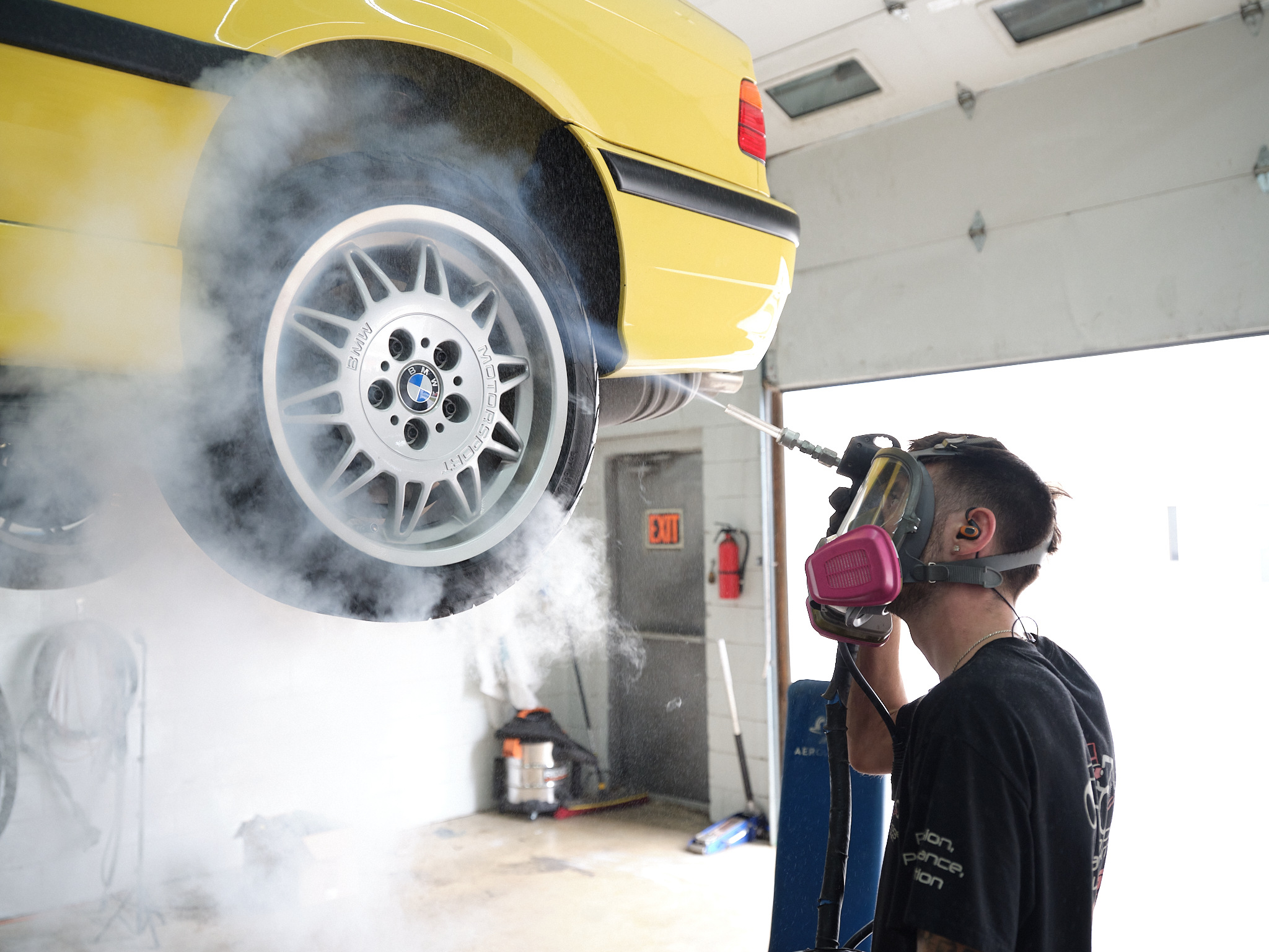 Dry ice cleaning machine is shown in action being used on a car wheel in a shop
